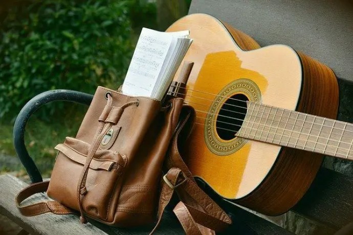 leather backpack sitting next to a guitar