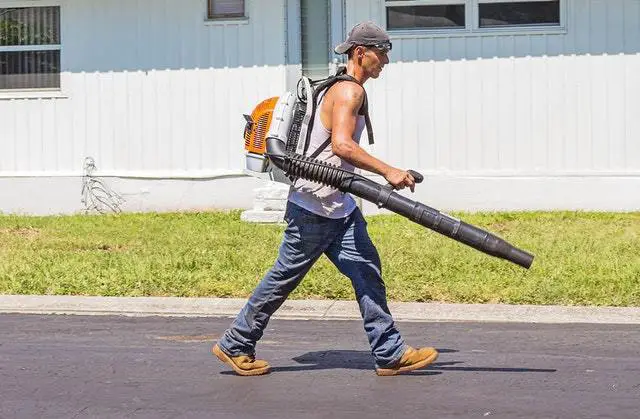 man in white with leaf blower