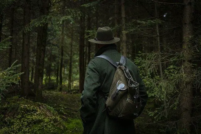 hunter in the forest wearing a backpack and hat