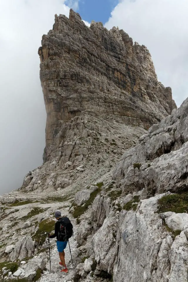 hiker climbing a mountain with trekking poles